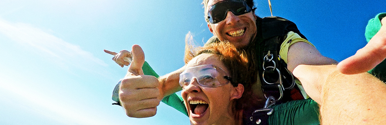 Uśmiechnięta kobieta i mężczyzna podczas skoku spadochronowego