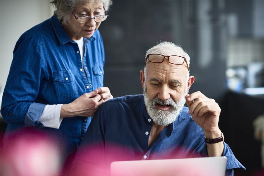 Starsza kobieta i mężczyzna wpatrują się w ekran komputera