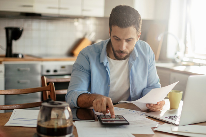 Mężczyzna podlicza swój budżet na kalkulatorze