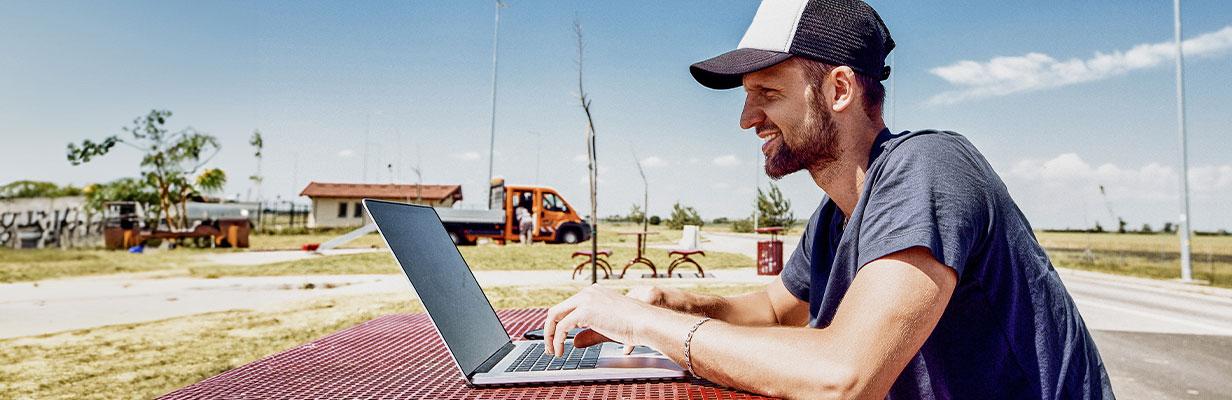 Mężczyzna w średnim wieku siedzi przy stoliku na zewnątrz, gdzieś w podróży podczas przerwy i prowadzi wideorozmowę z ekspertem hipotecznym z ING.