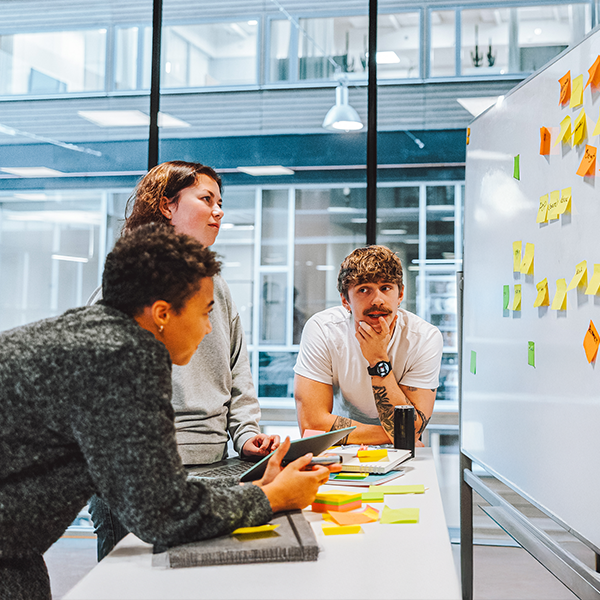 Troje ludzi podczas pracy przy białej tablicy z karteczkami post-stick