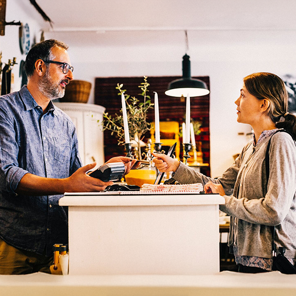 Mężczyzna przyjmujący na terminalu płatność kartą od kobiety