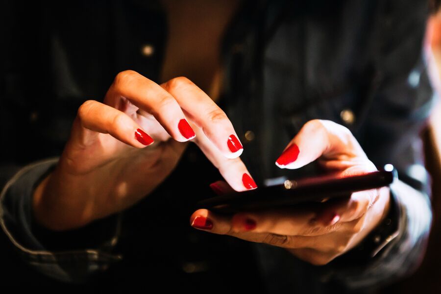 Kobieta trzyma telefon. Widoczne są tylko dłonie