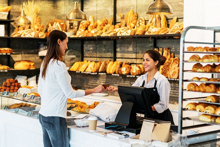 Kobieta w piekarni płaci kartą na terminalu płatniczym