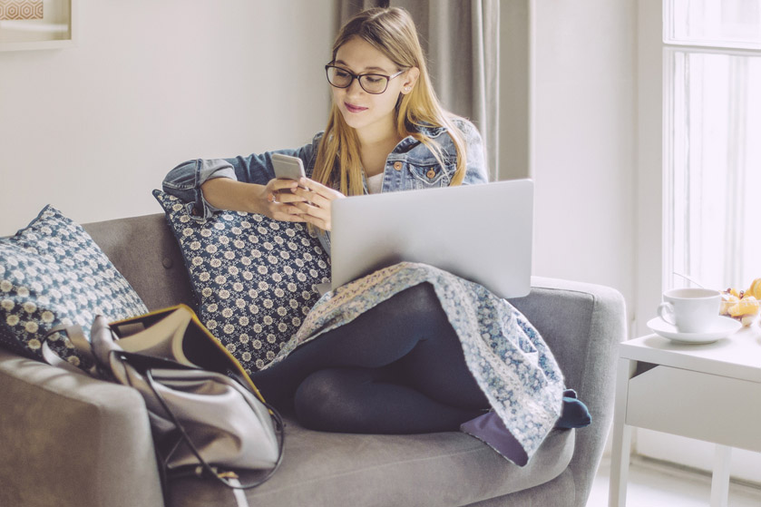 Kobieta siedzi na kanapie i sprawdza coś w telefonie