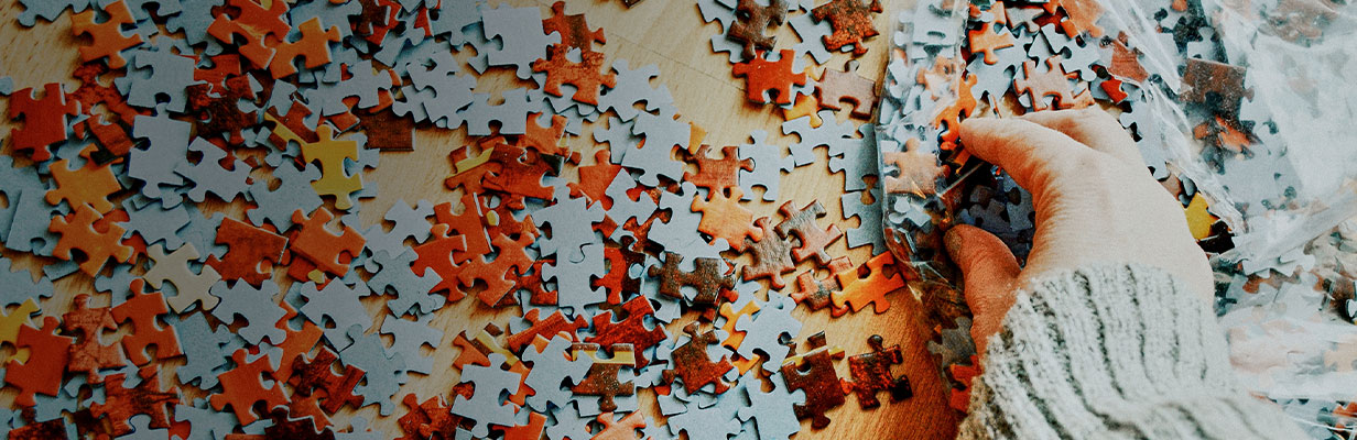 Ręce osoby układającej kolorowe puzzle – widok z góry.