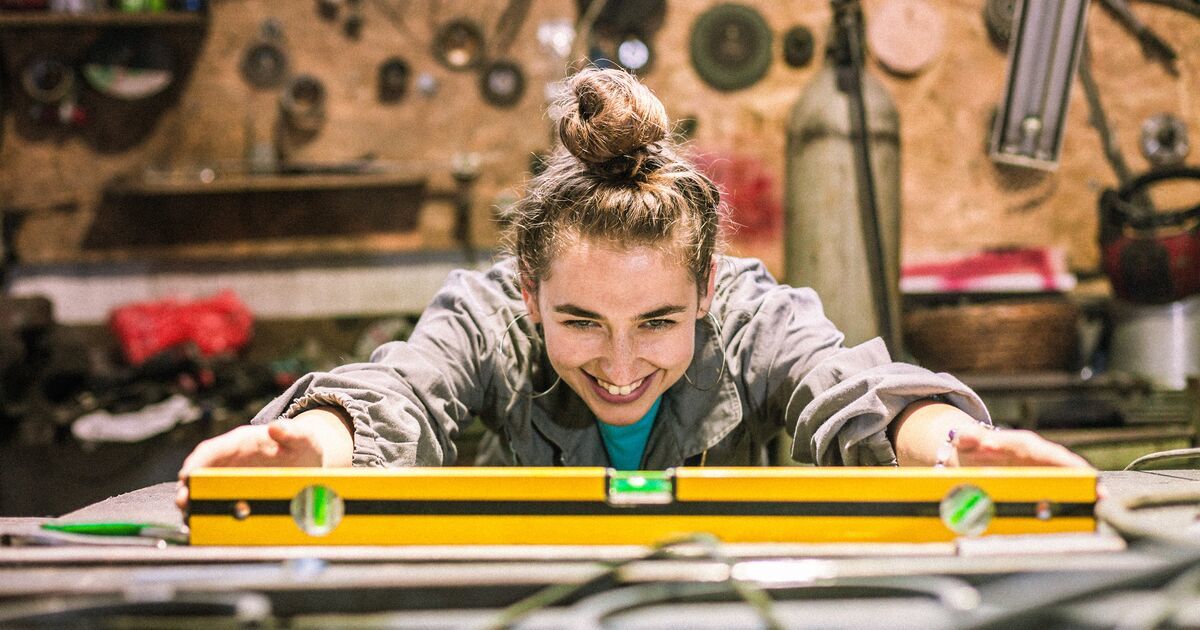 Kobieta w warsztacie, która trzyma w ręce poziomicę