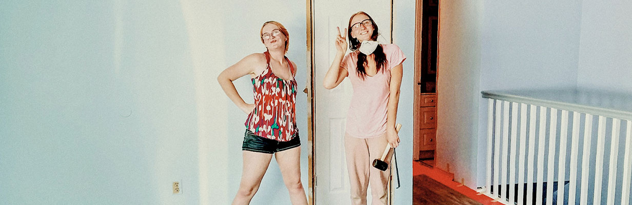 Dwie młode kobiety w nowym mieszkaniu podczas remontu. Uśmiechają się i wygłupiają, trzymając w rękach narzędzia.