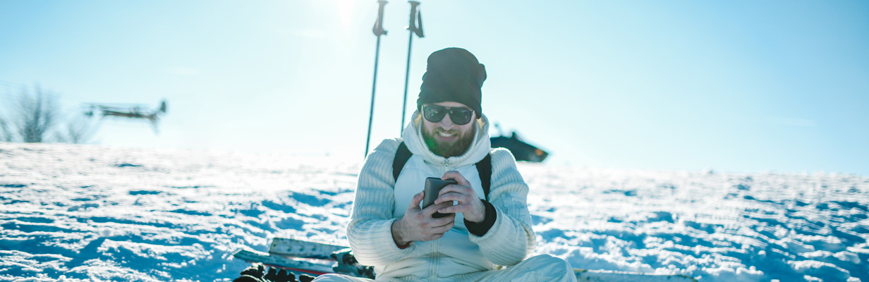 skupiony mężczyzna na stoku z telefonem w ręku