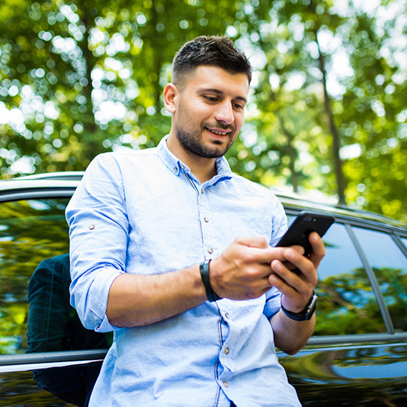 Oparty o samochód mężczyzna z telefonem w ręku