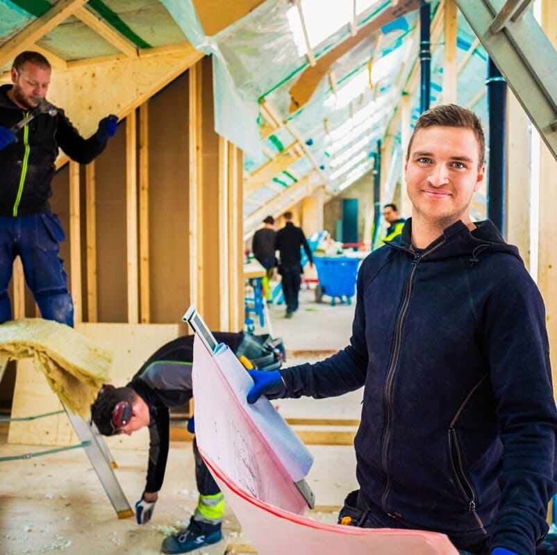 Młody przedsiębiorca pozuje na tle placu budowy