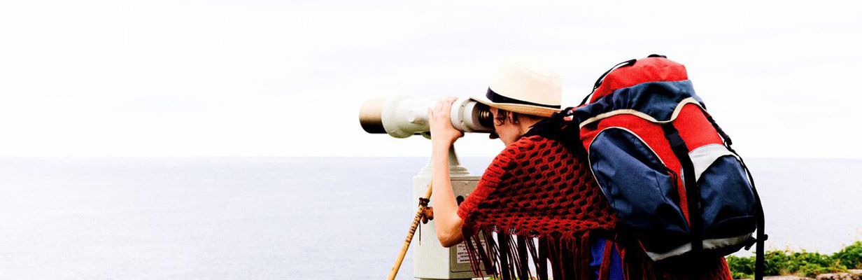 Mężczyzna ogląda nadmorski widok przez lornetkę
