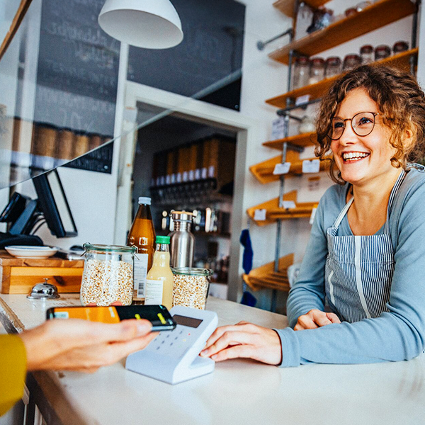 Kobieta w swoim sklepie przyjmująca płatność na terminalu