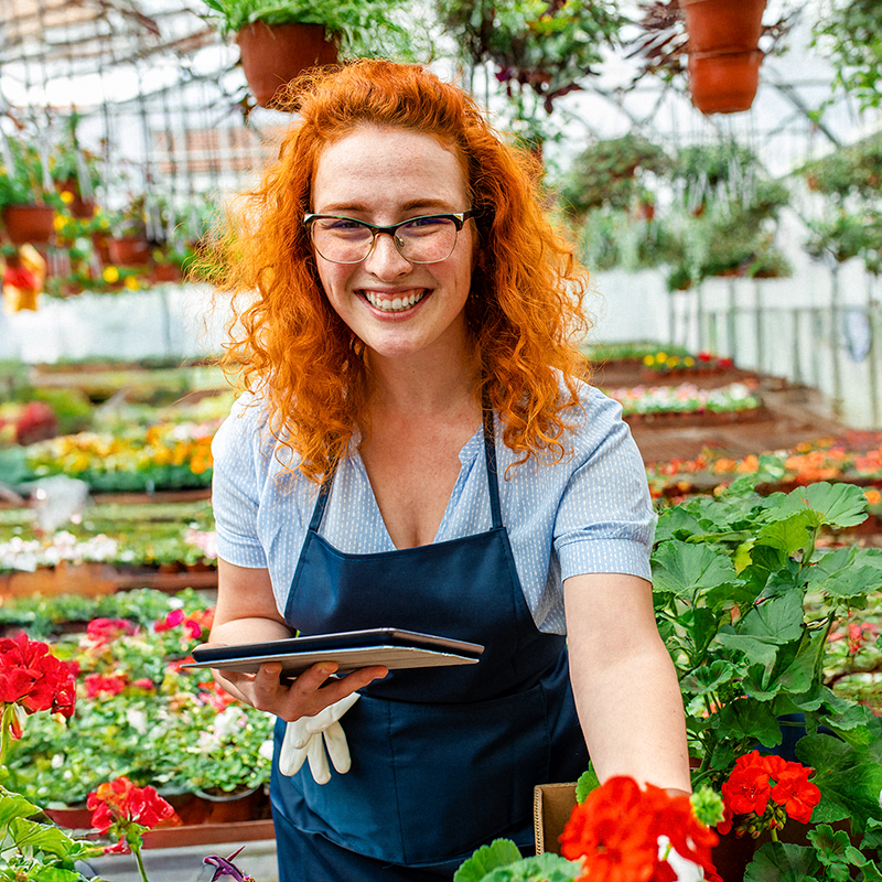 Młoda przedsiębiorczyni podczas pracy w szklarni z roślinami