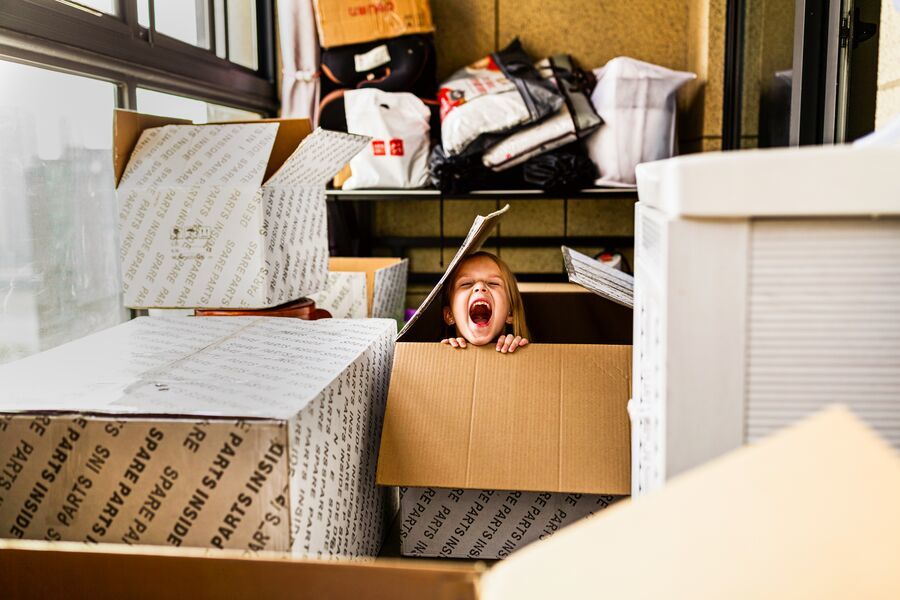 Roześmiana dziewczynka chowa się w kartonowym pudełku