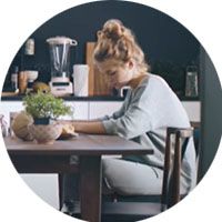 Zdjęcie kobiety, która siedzi przy stole i pisze.