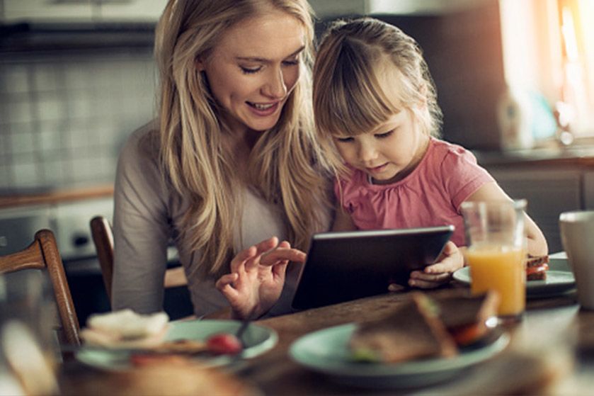 Matka z dzieckiem na kolanach. Kobieta trzyma w rękach tablet i wspólnie patrzą na ekran