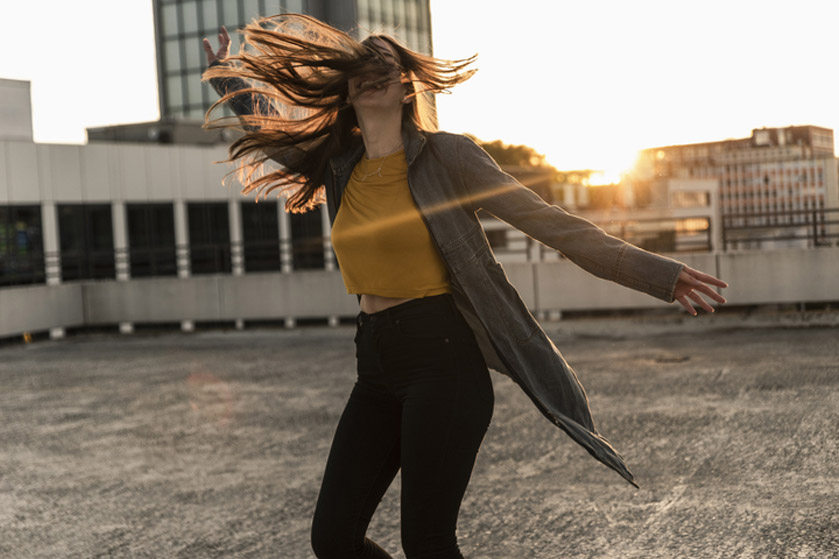 Dziewczyna tańczy na dachu wieżowca. Jest bezpieczna, otoczona wysokimi barierkami. Cieszy się chwilą