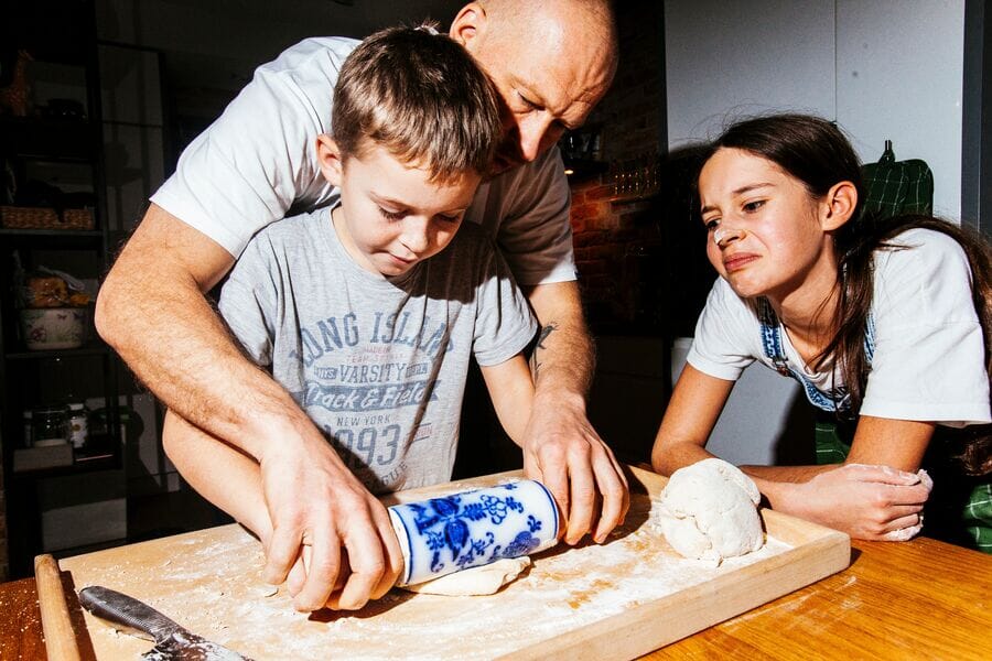 Ojciec z synem wyrabiają ciasto w kuchni