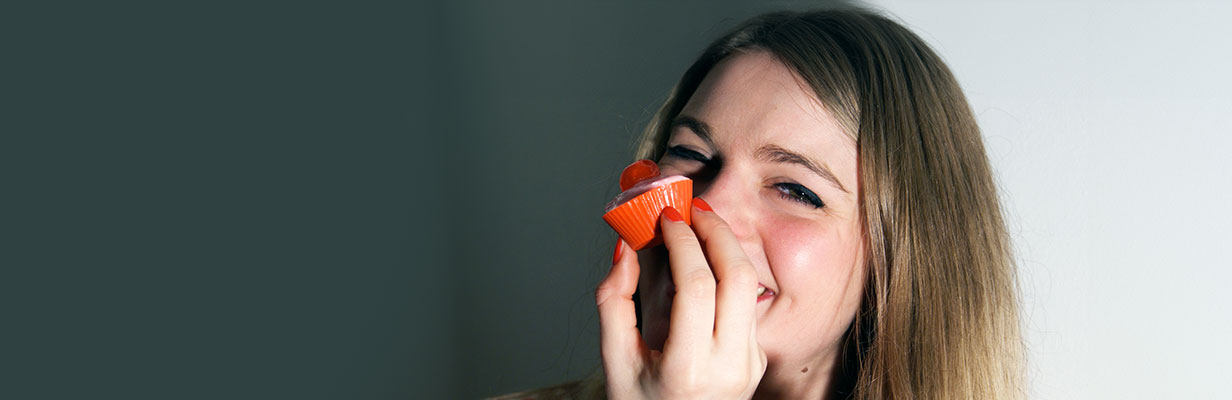 Uśmiechnięta dziewczyna trzymająca truskawkę na wysokości nosa, grafika wyrażająca radość