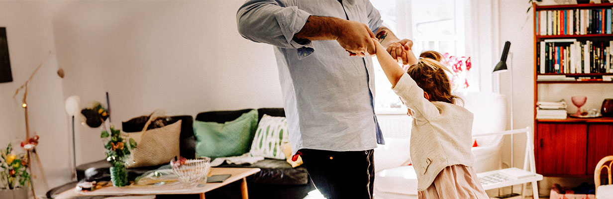 Tata z córką wygłupiają się w nowym mieszkaniu - trzymają się za ręce i kręcą w koło.