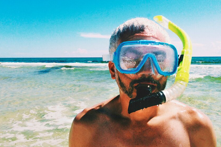 Meżczyzna pływa w morzu z maską do snorkelingu